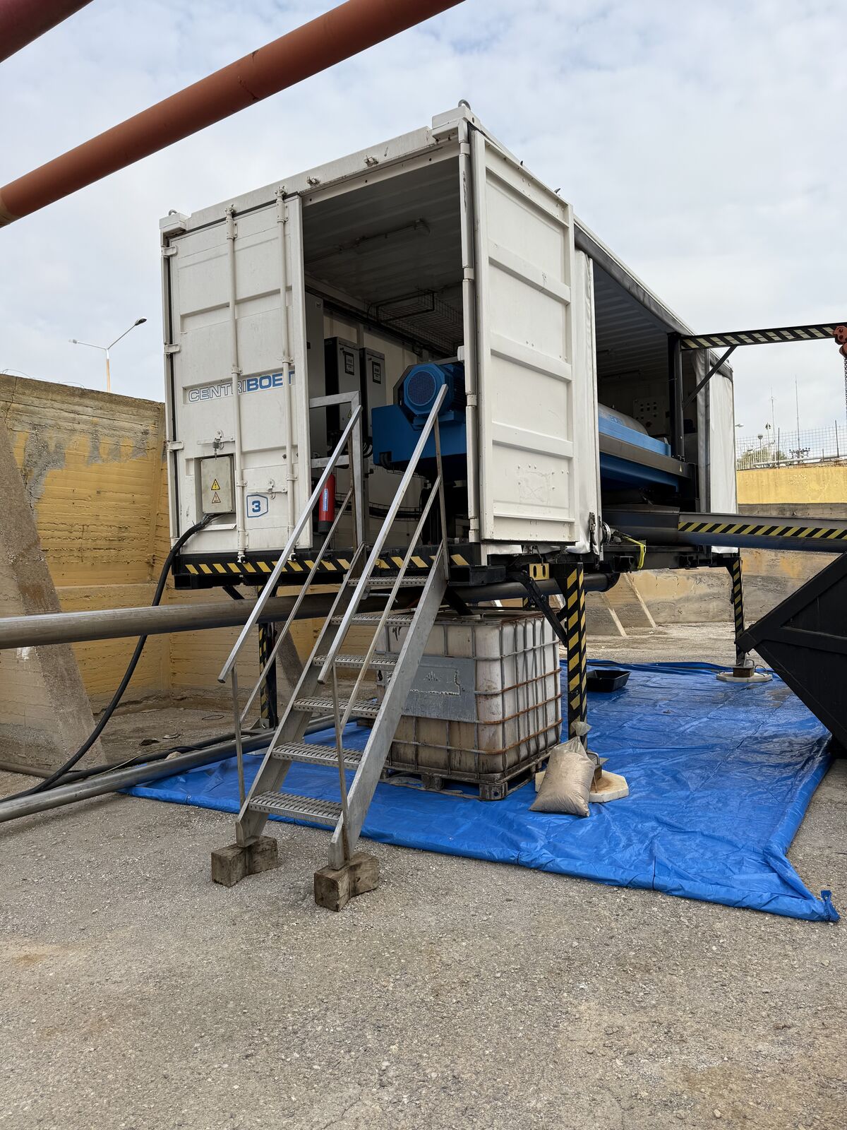 Vacuum unit and cab parked alongside a tank cleaning operation