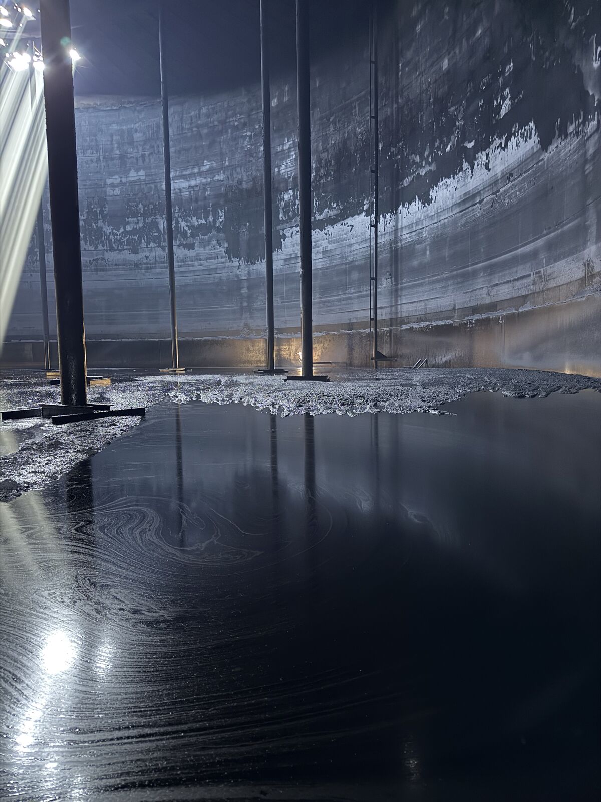 Cleaned tank interior with wet-floor reflections at hand-back