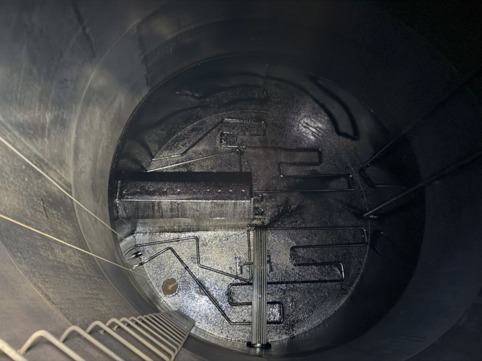 Heavy hydrocarbon sludge across a tank floor before cleaning