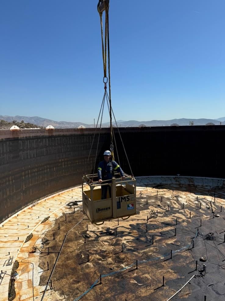 Operator being lowered into a tank in a personnel basket