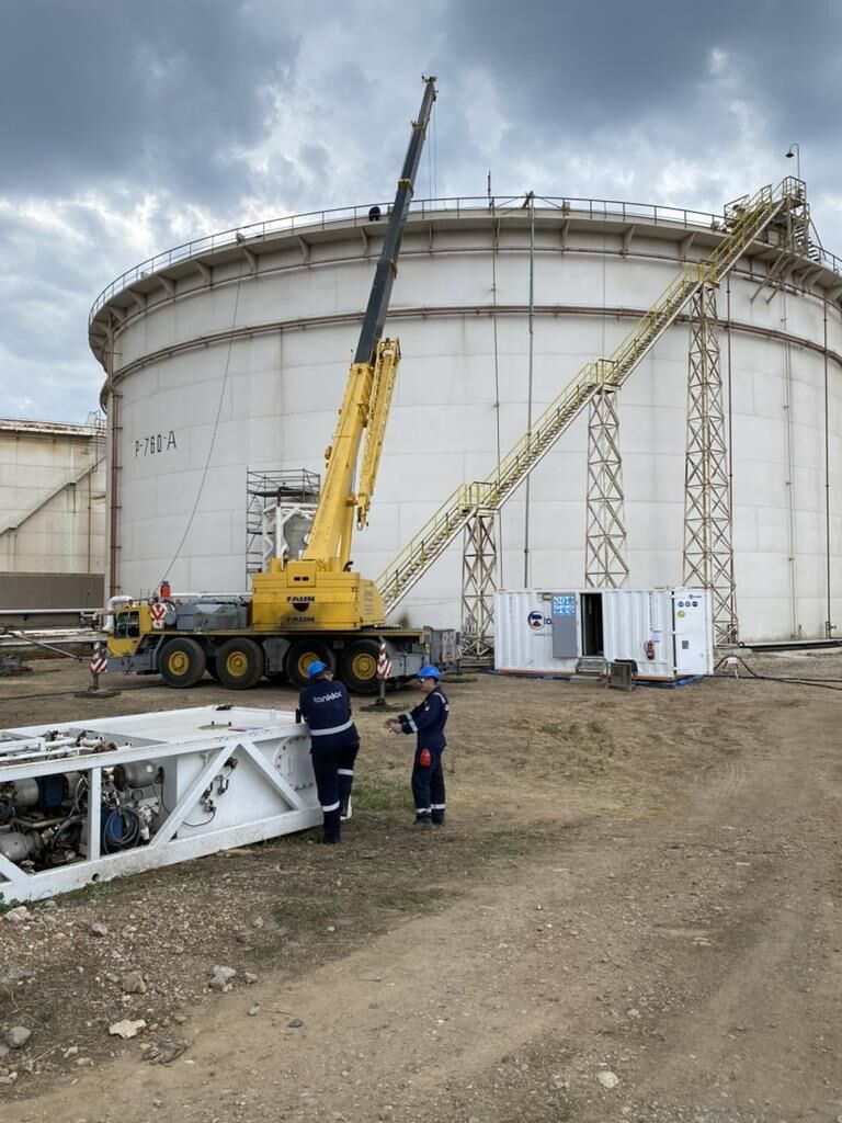 Crane positioned at a storage tank for sludge extraction