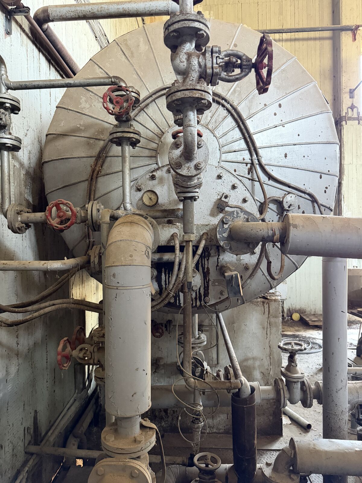 Process vessel with valves and piping inside a chemical-plant building